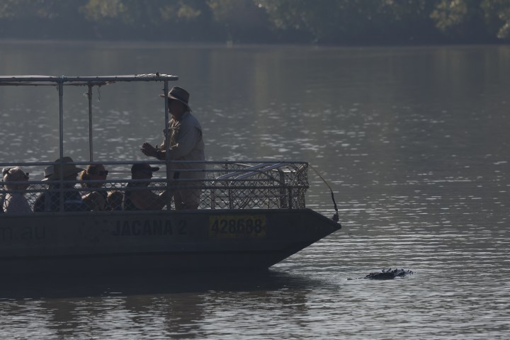 Group on a boat in water with a guide pointing towards nearby floating object.